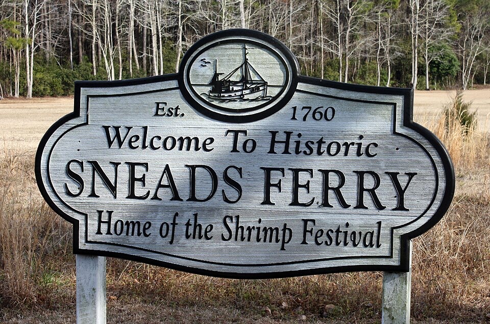 Carved wooden sign reading Welcome to Historic Sneads Ferry, Home of the Shrimp Festival, established 1760